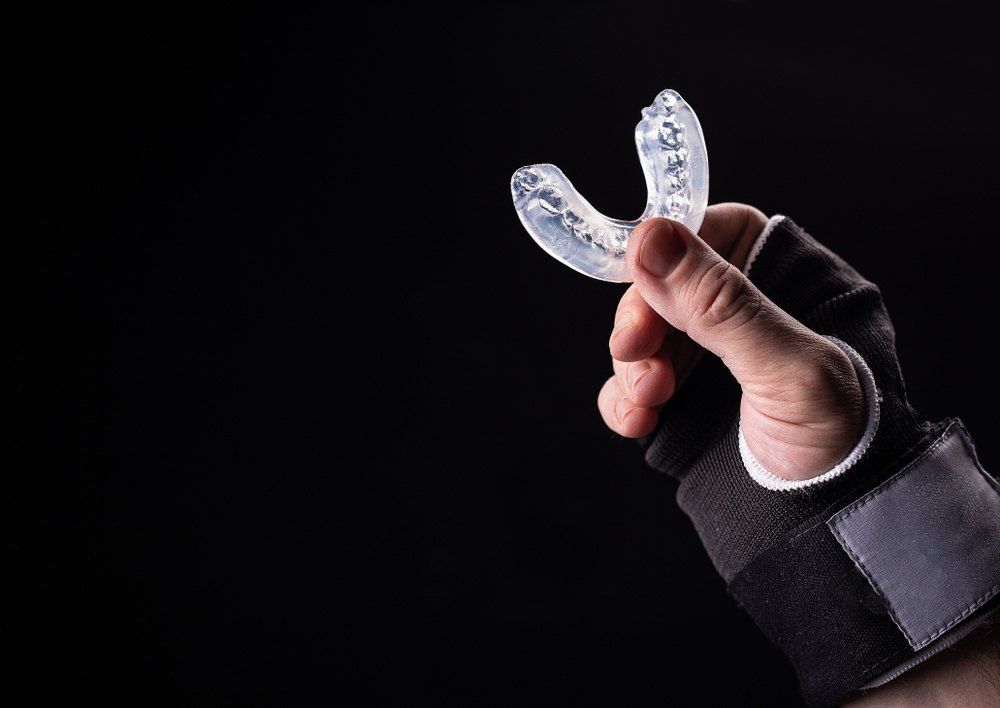 A Person is Holding a Mouth Guard in Their Hand — Complete Denture Clinic in Kanwal, NSW