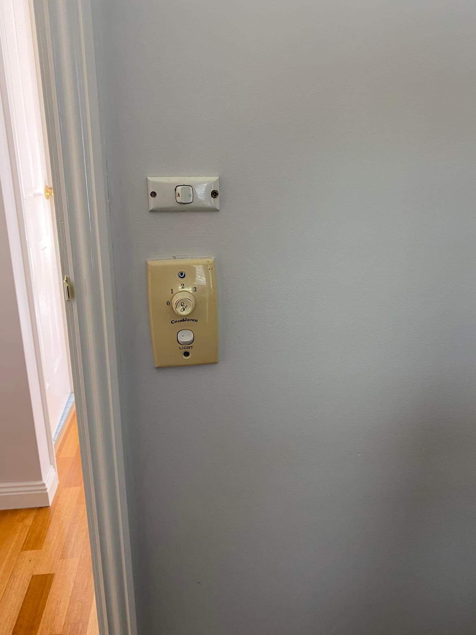 Two Light Switches on a Gray Wall Next to a Doorway — SparkSafe Electrical in Dapto, NSW