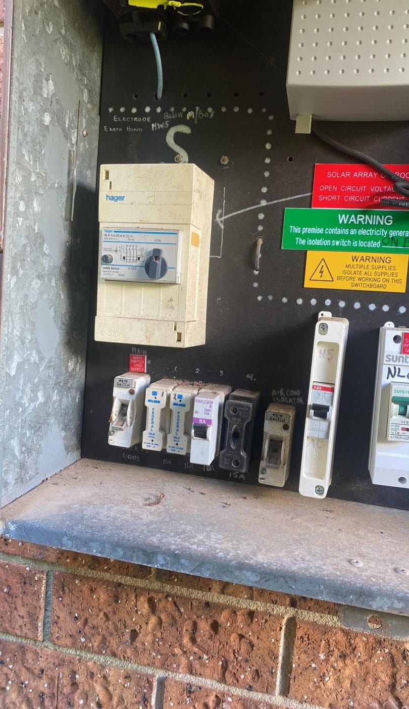 Electrical Panel With Switches and Fuses Mounted on a Brick Wall — SparkSafe Electrical in Dapto, NSW