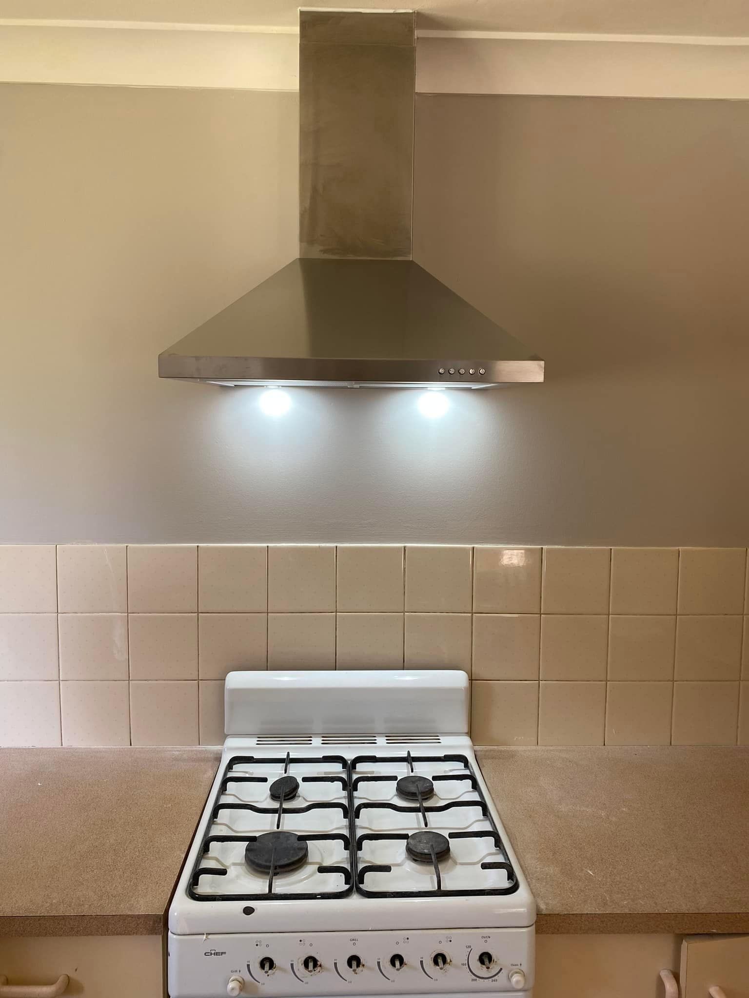 Stainless Steel Range Hood Above a Gas Stove — SparkSafe Electrical in Kiama, NSW