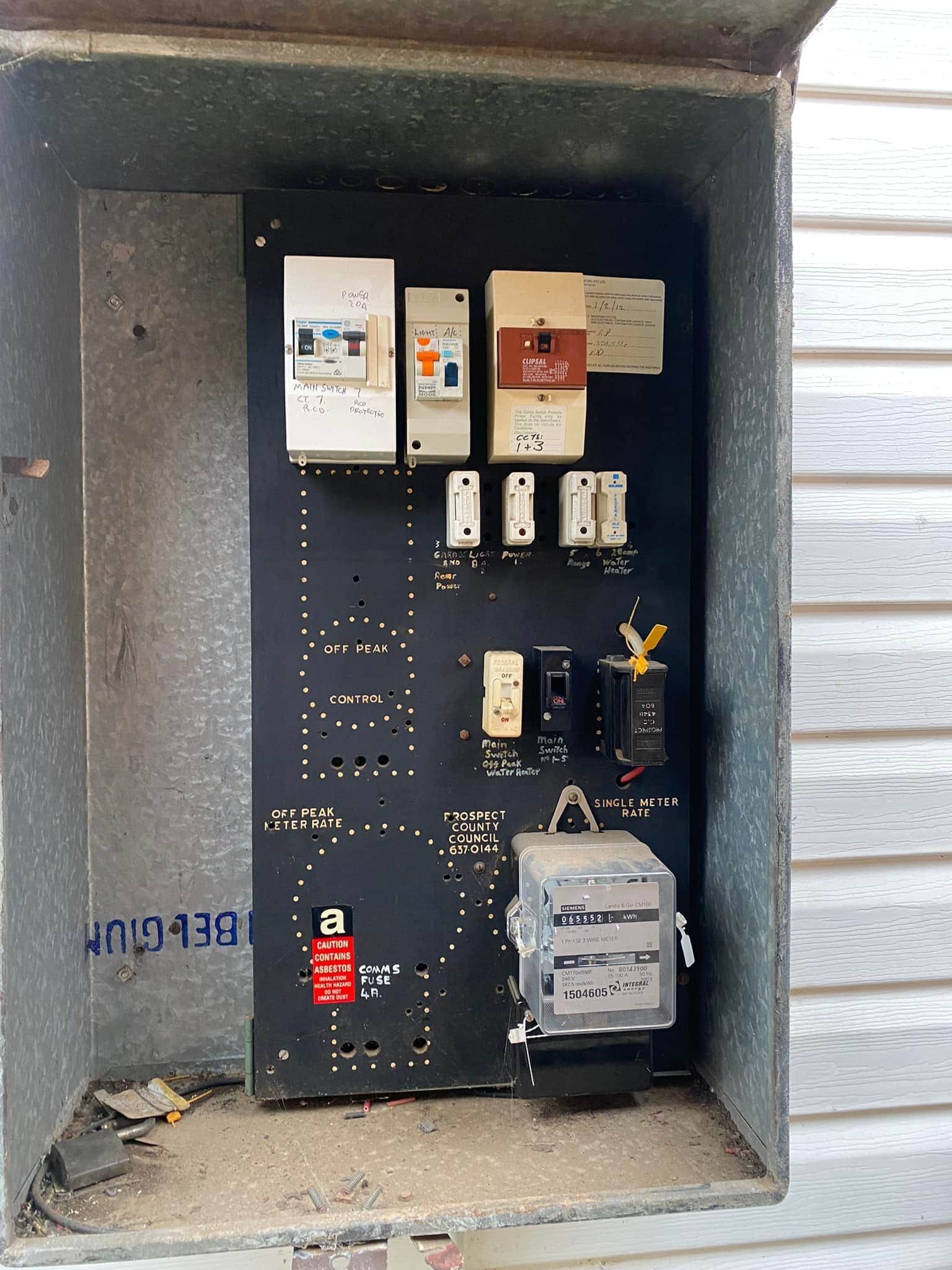 Electrical panel with various switches and fuses, mounted inside a metal box on a wall  — SparkSafe Electrical in Dapto, NSW
