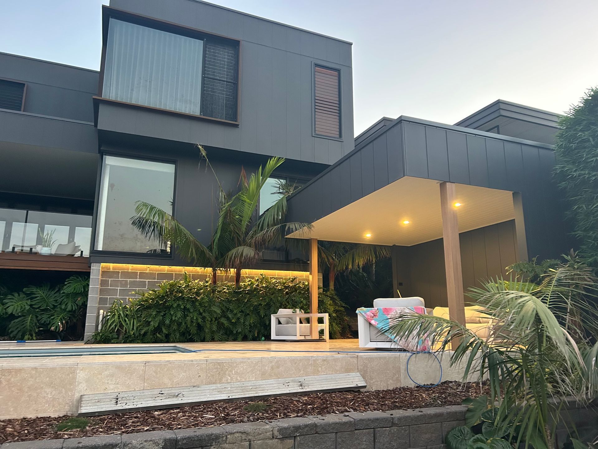 Modern gray house with large windows, covered patio, and outdoor landscaping  — SparkSafe Electrical in Dapto, NSW