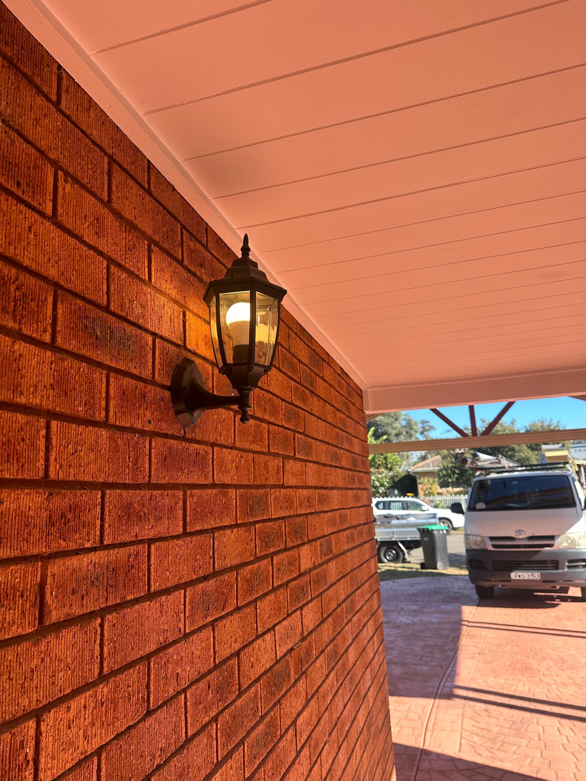 Brick wall with a black decorative outdoor light under a white ceiling — SparkSafe Electrical in Gerringong, NSW