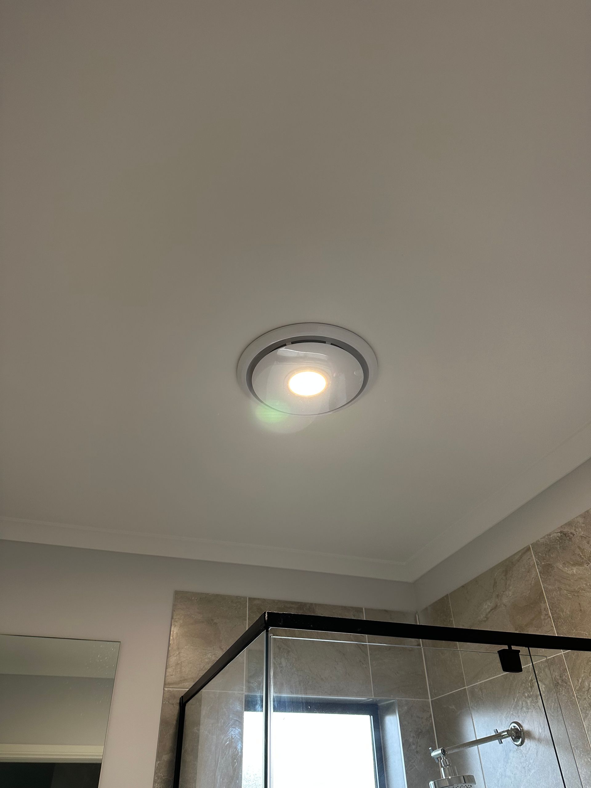 Ceiling light fixture in a bathroom. White ceiling, circular light with a green indicator — SparkSafe Electrical in Kiama, NSW