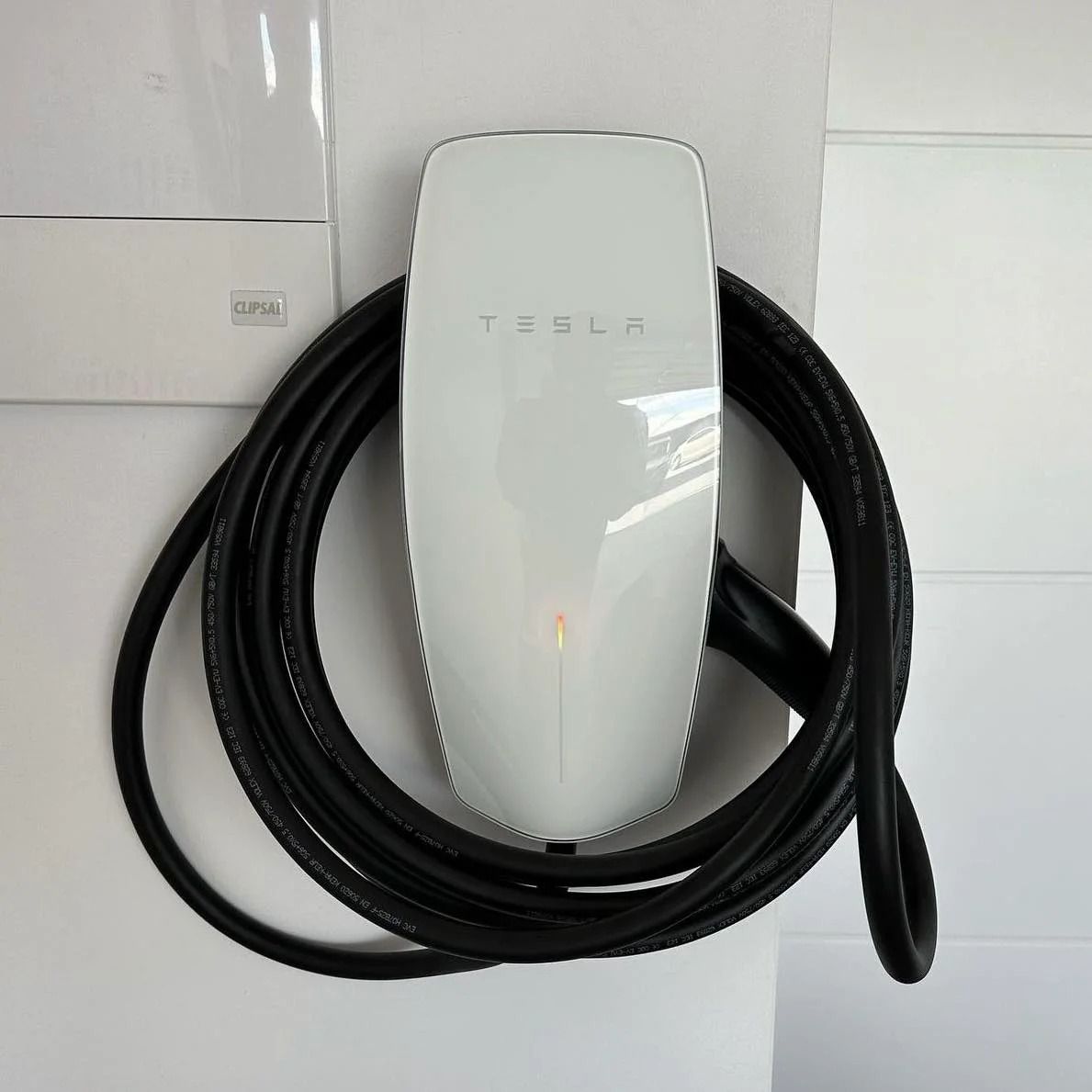 Tesla Wall Connector charging station with coiled black cable — SparkSafe Electrical in Gerringong, NSW