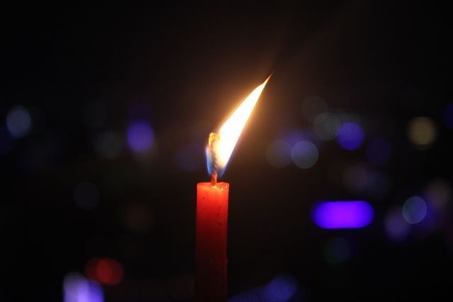 Close-up of a glowing candle flame in a dark ambiance in Scarborough, ME, representing remembrance, reflection, and memorial services