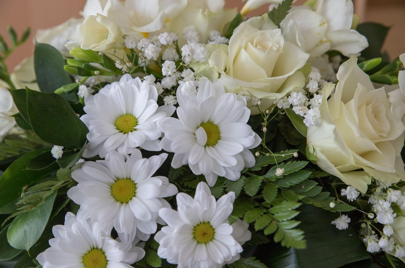 white funeral flower arrangement with roses, daisies, baby’s breath, and green foliage in scarborough, me