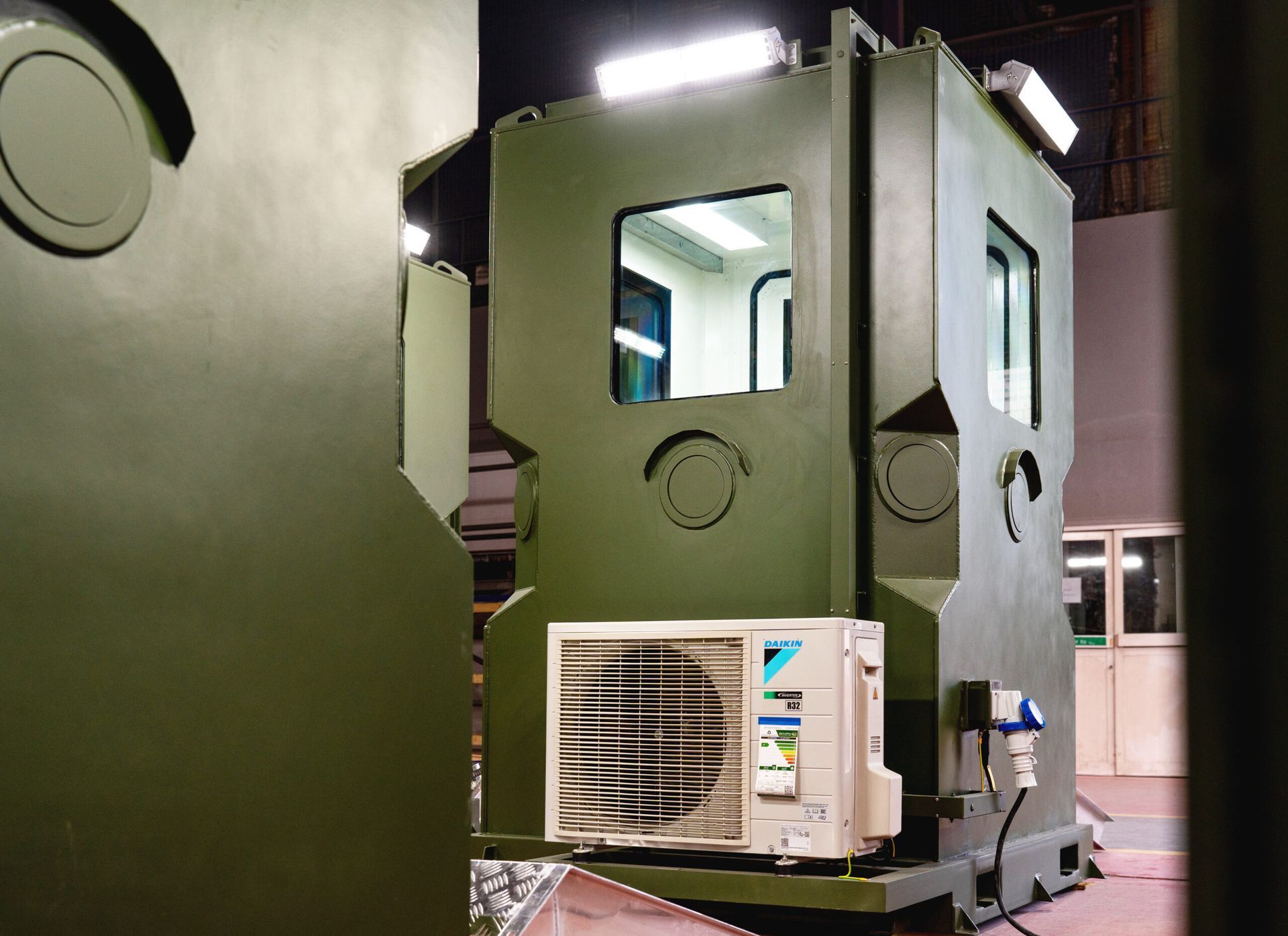 Green industrial structure with windows, air conditioner, and round details. Workshop interior.