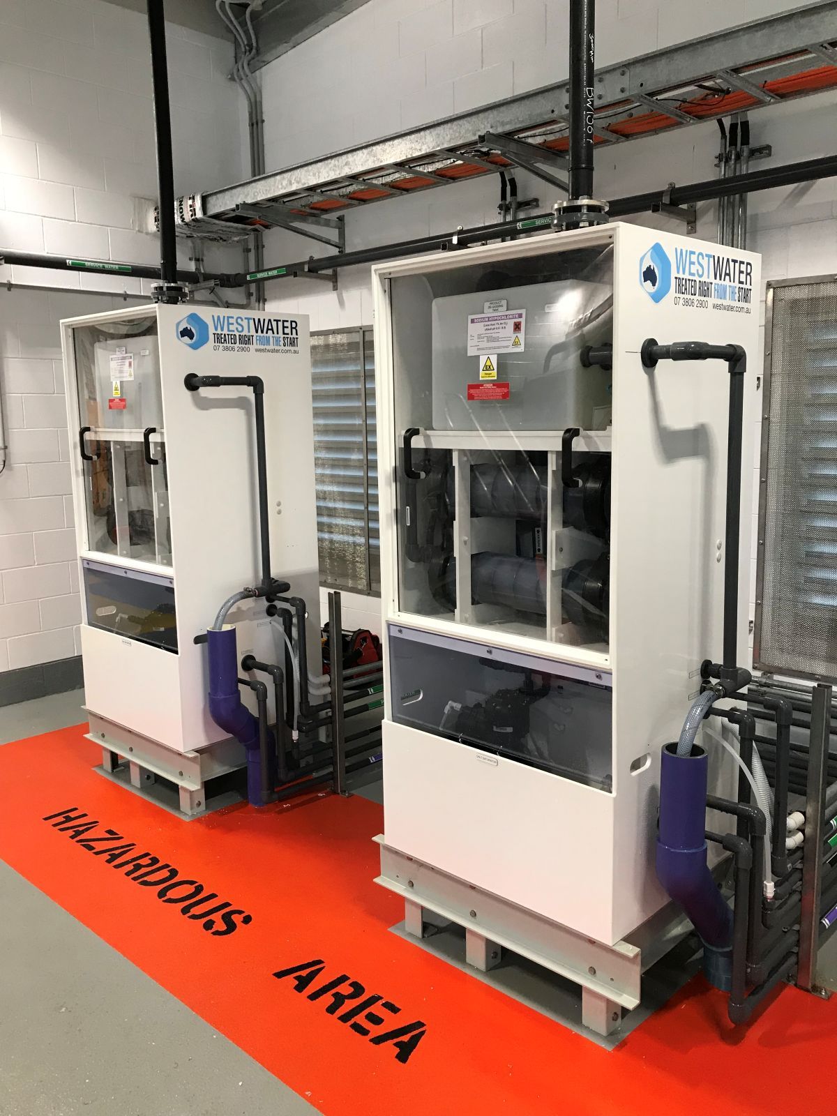 Two white water treatment machines in a room, with hazardous area floor mat.