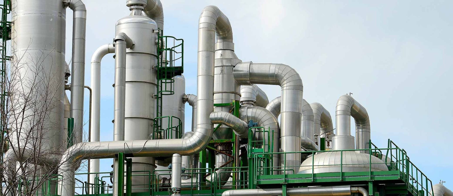 Geothermal plant with large silver pipes and green structures under a bright sky
