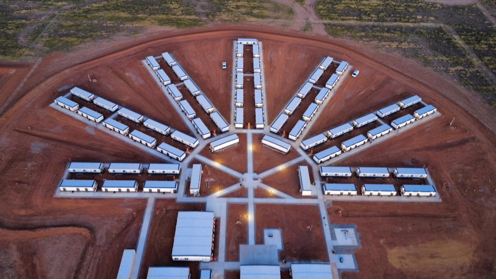 Aerial view of a complex with many rectangular buildings arranged in a starburst pattern on brown land.