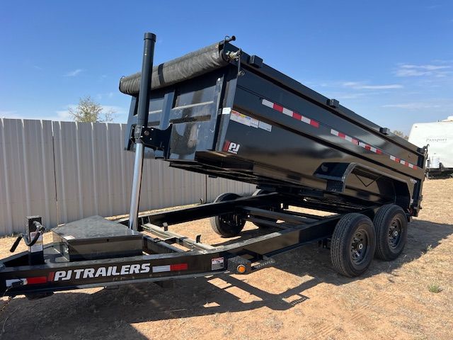 A dump trailer is parked in a dirt field.