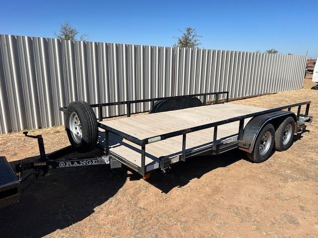 A flatbed trailer is parked in front of a metal fence.