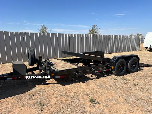 A trailer is parked in the dirt in front of a fence.