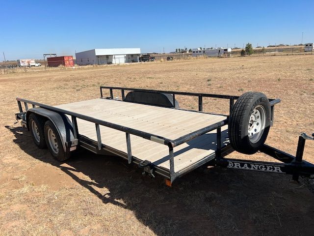 A trailer is parked in the middle of a dry grass field.