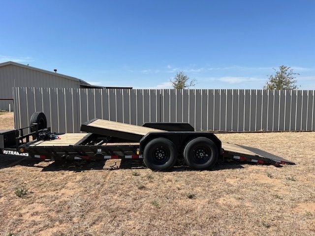 A trailer is parked in a field next to a fence.