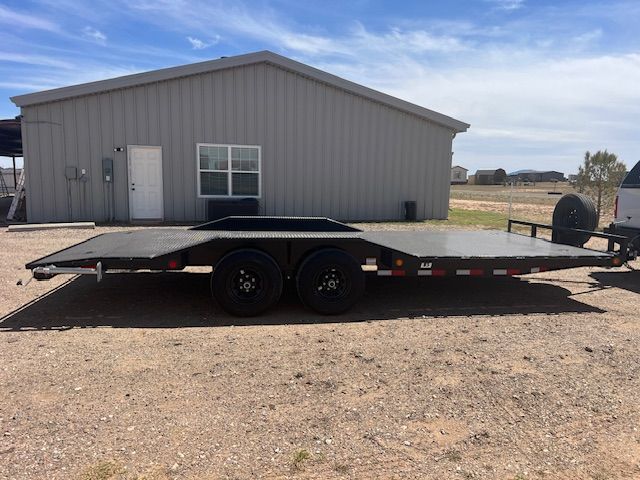 A flatbed trailer is parked in front of a building