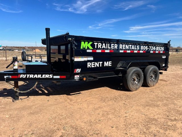 A dump trailer is parked in a dirt field.