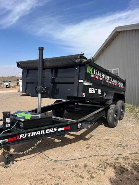 A dump trailer is parked in front of a building.