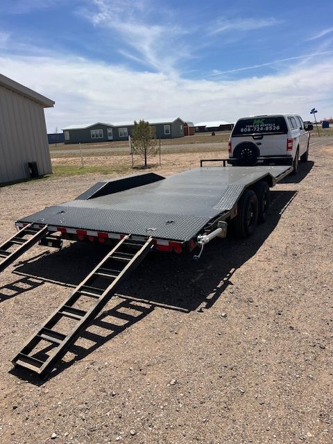 A white truck is parked behind a flatbed trailer