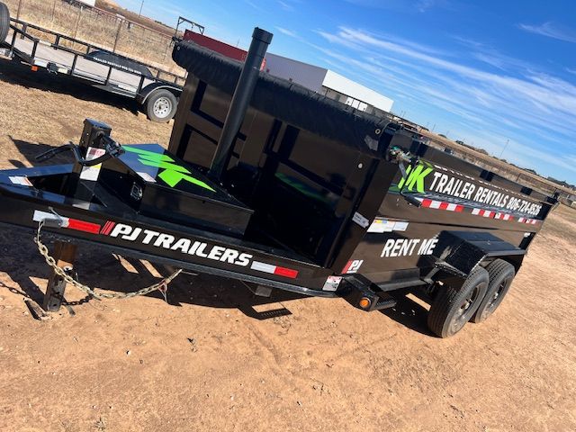 A dump trailer is parked in a dirt field.