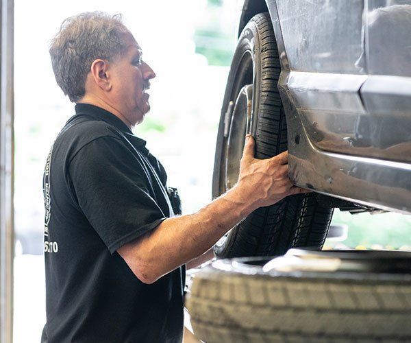 A man in a black shirt is working on a car in a garage.