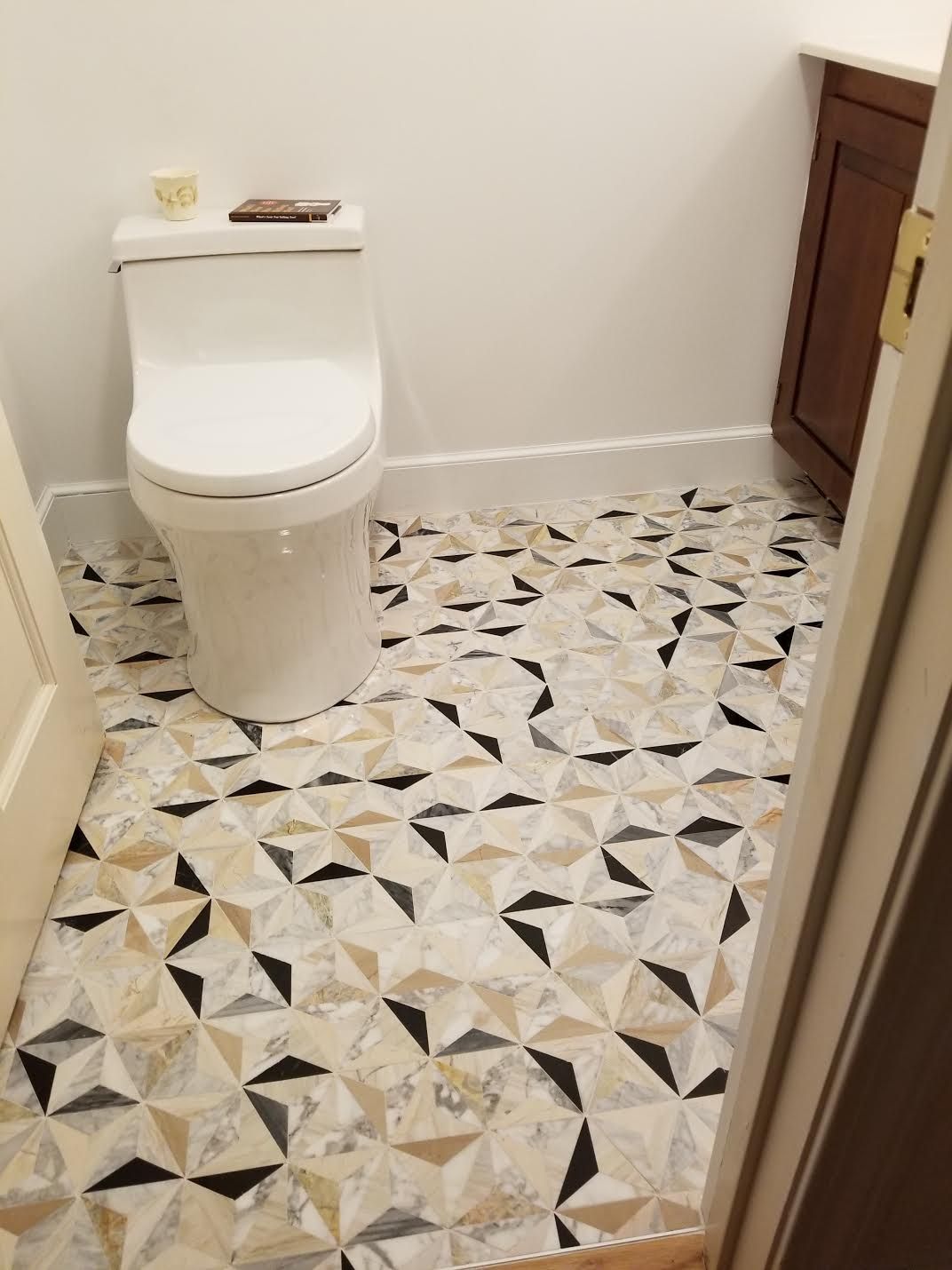 A toilet is sitting on a tiled floor in a bathroom.
