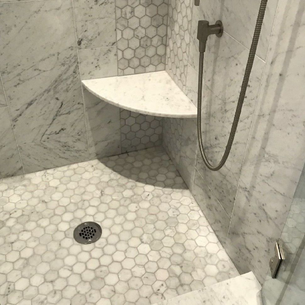 A shower with a seat and a drain in the floor