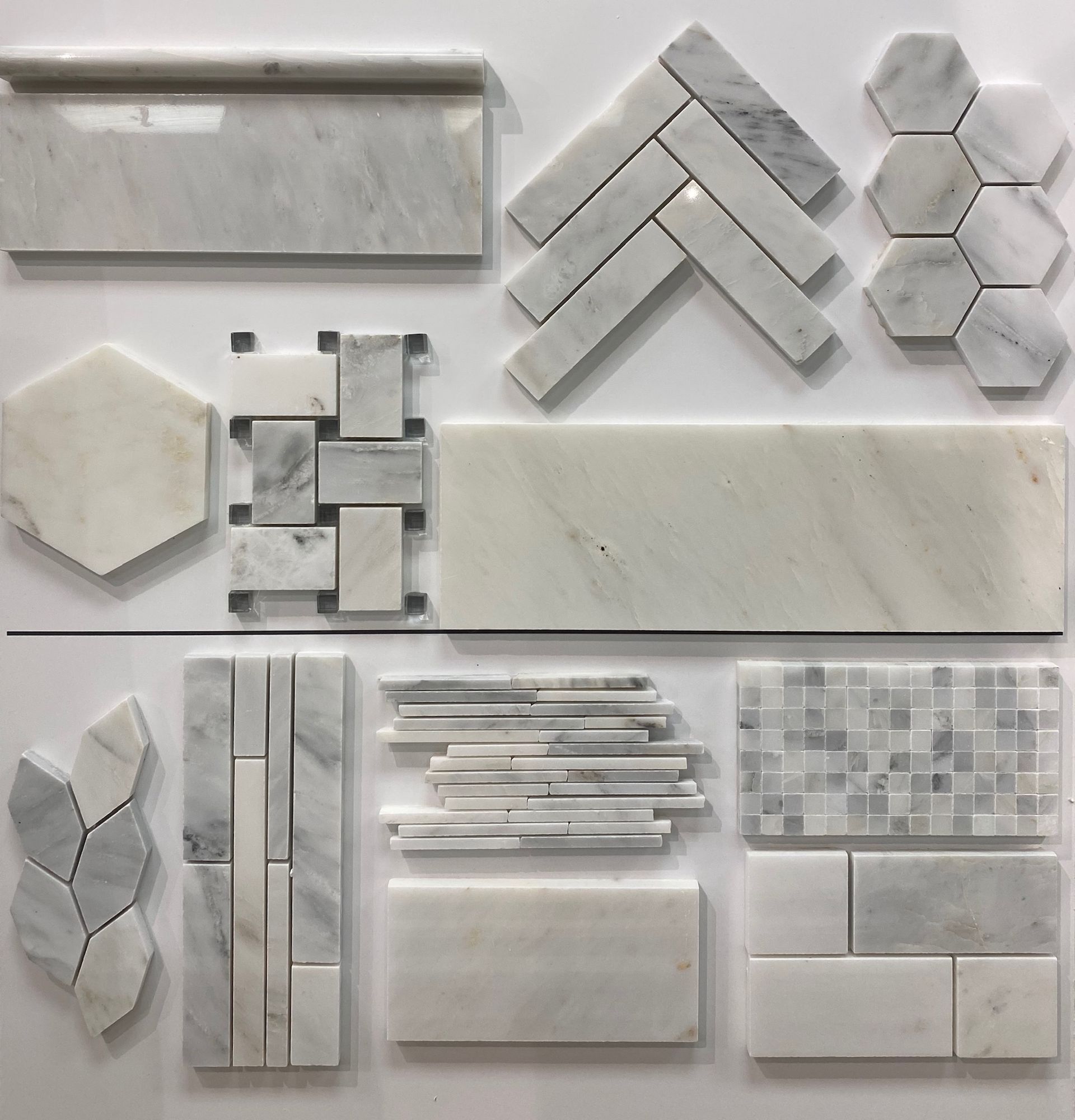 A variety of white marble tiles are displayed on a white surface