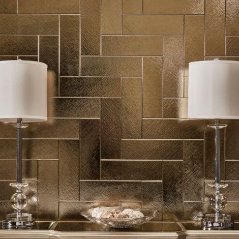 Two lamps are sitting on a table in front of a gold tiled wall.