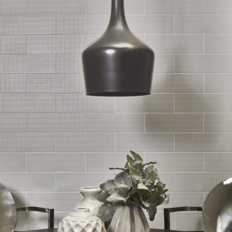 A table with vases and plates on it and a lamp hanging from the ceiling.