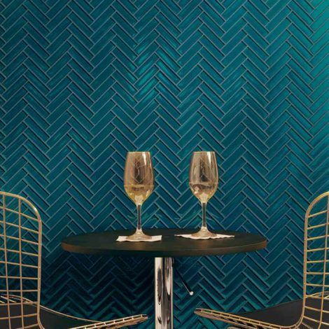 Two glasses of wine are on a table in front of a blue wall.