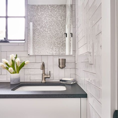 A bathroom with a sink , mirror , and window.