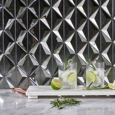 Two glasses of gin and tonic with limes and rosemary on a marble cutting board.