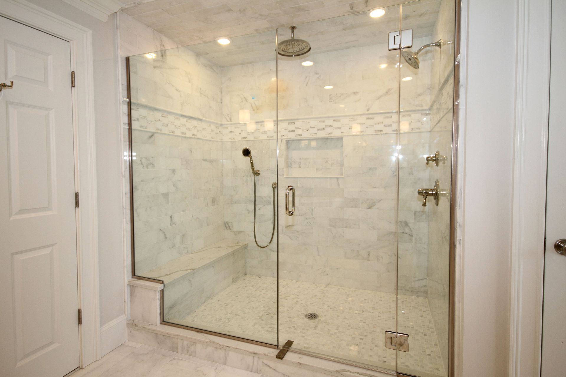 A bathroom with a walk in shower with a glass door.