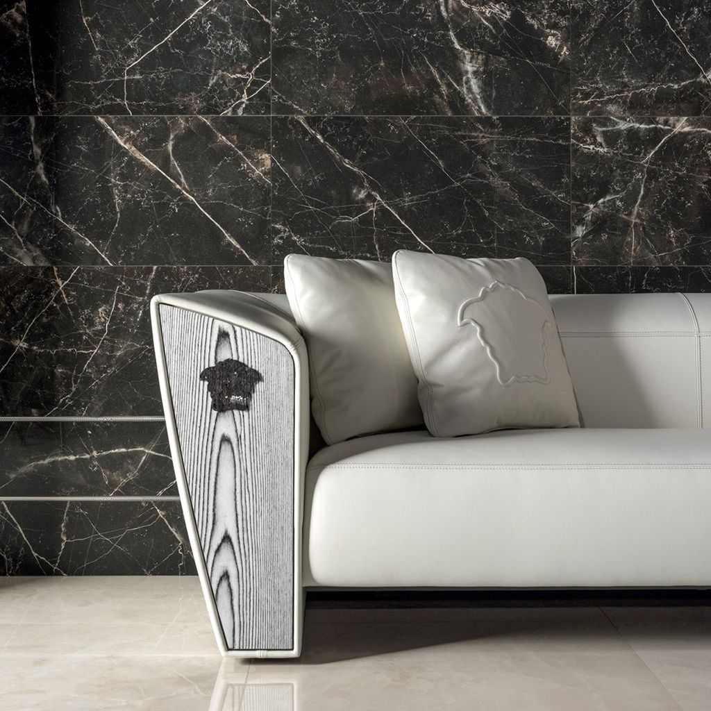 A white couch in front of a black marble wall