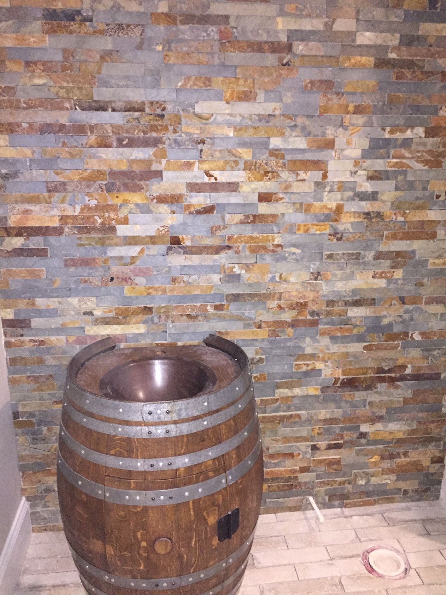 A wooden barrel is sitting in front of a stone wall.