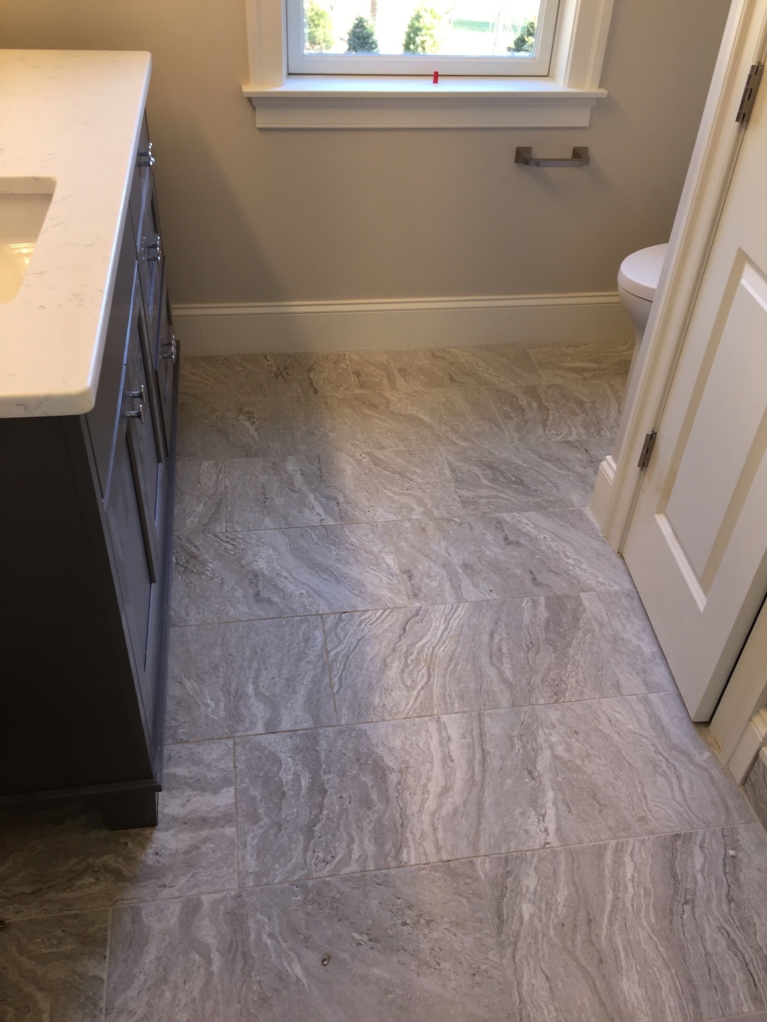 A bathroom with a sink , toilet and window.