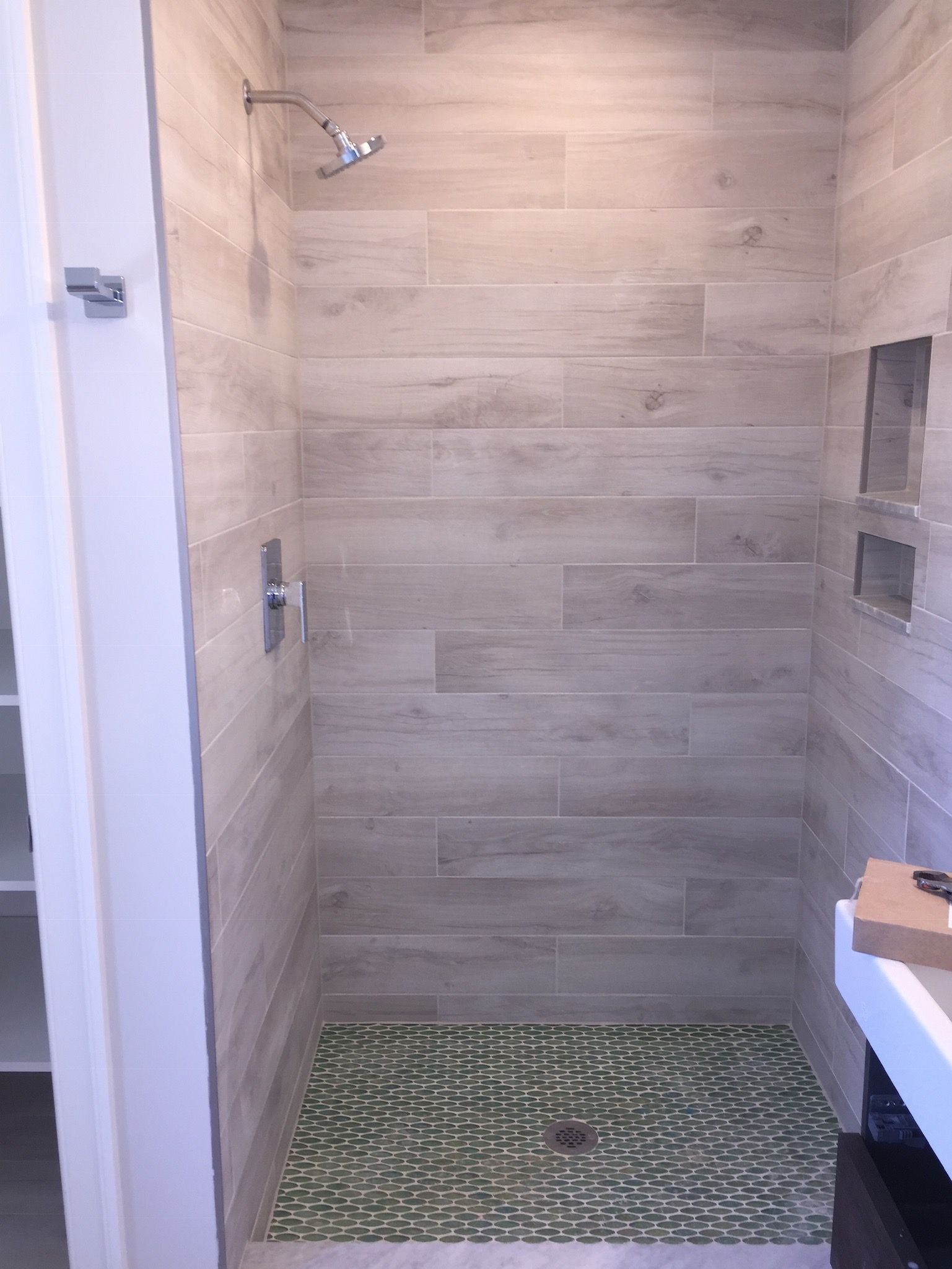 A bathroom with a walk in shower and a green tile floor.