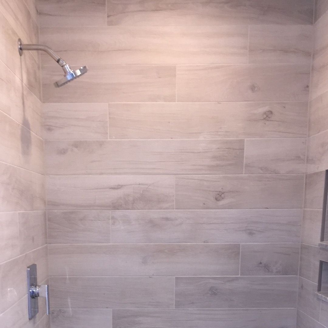 A shower with a wooden wall and a shower head.