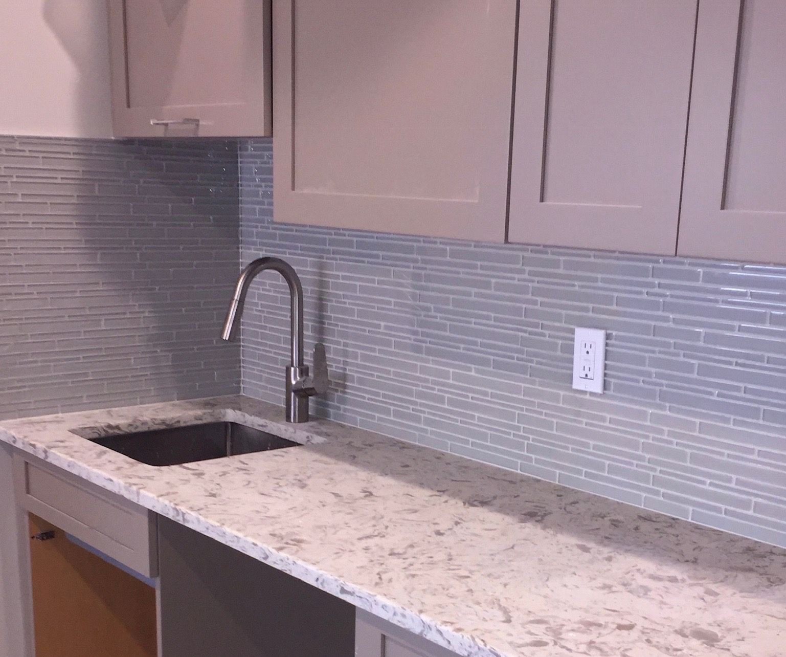A kitchen with a sink , faucet and cabinets.