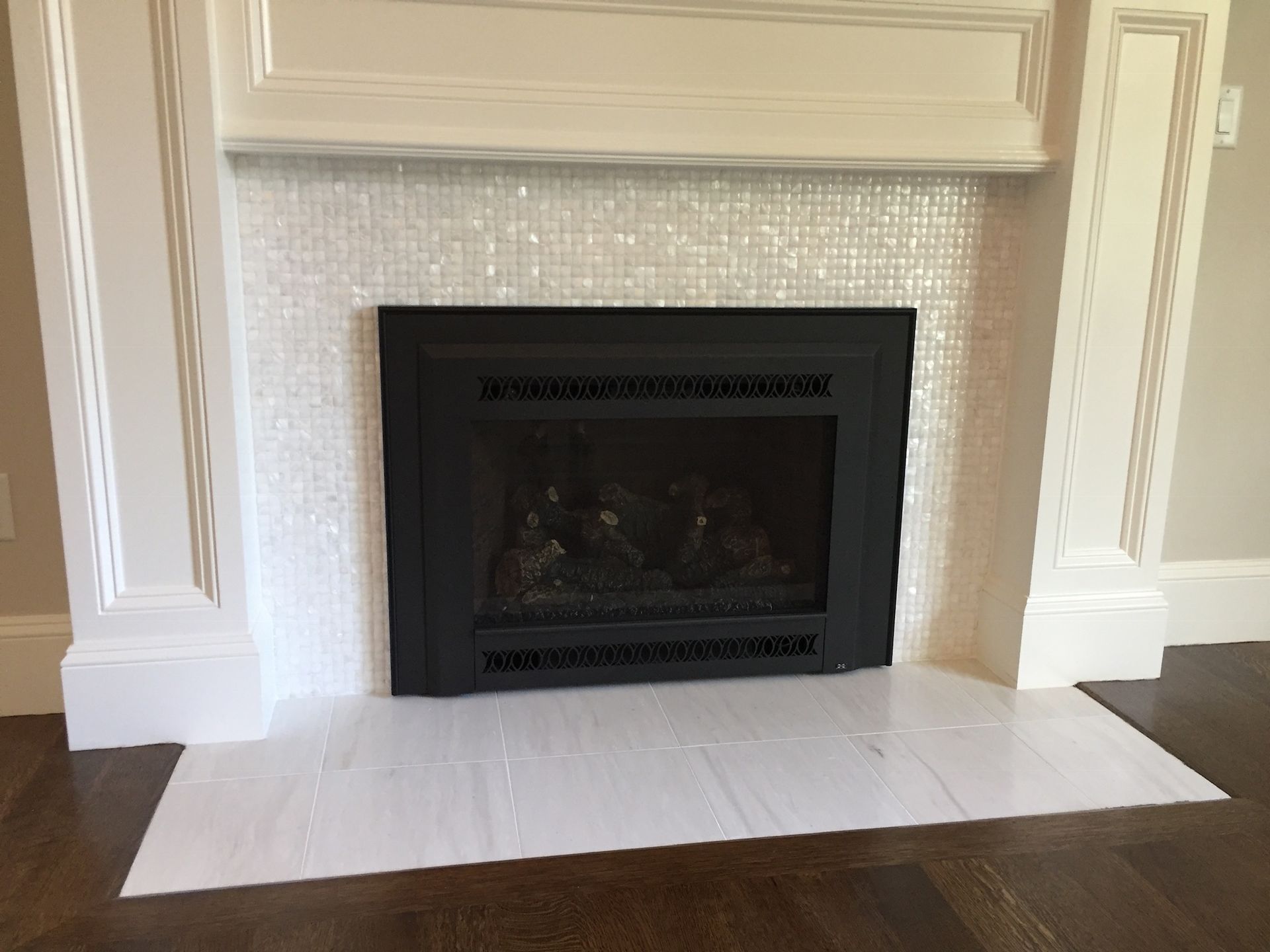 A fireplace with a white tile surround and a black door