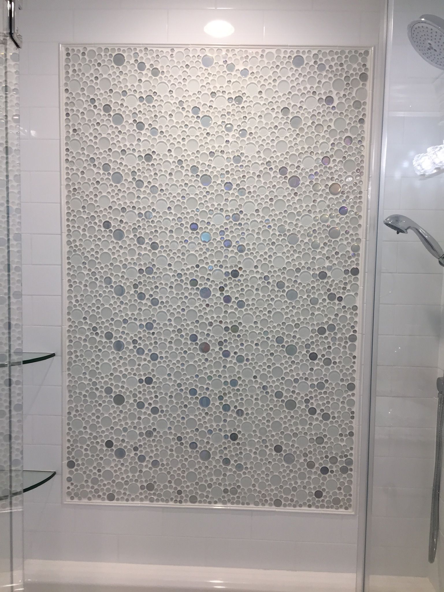 A shower stall with a tiled wall and a shower head.