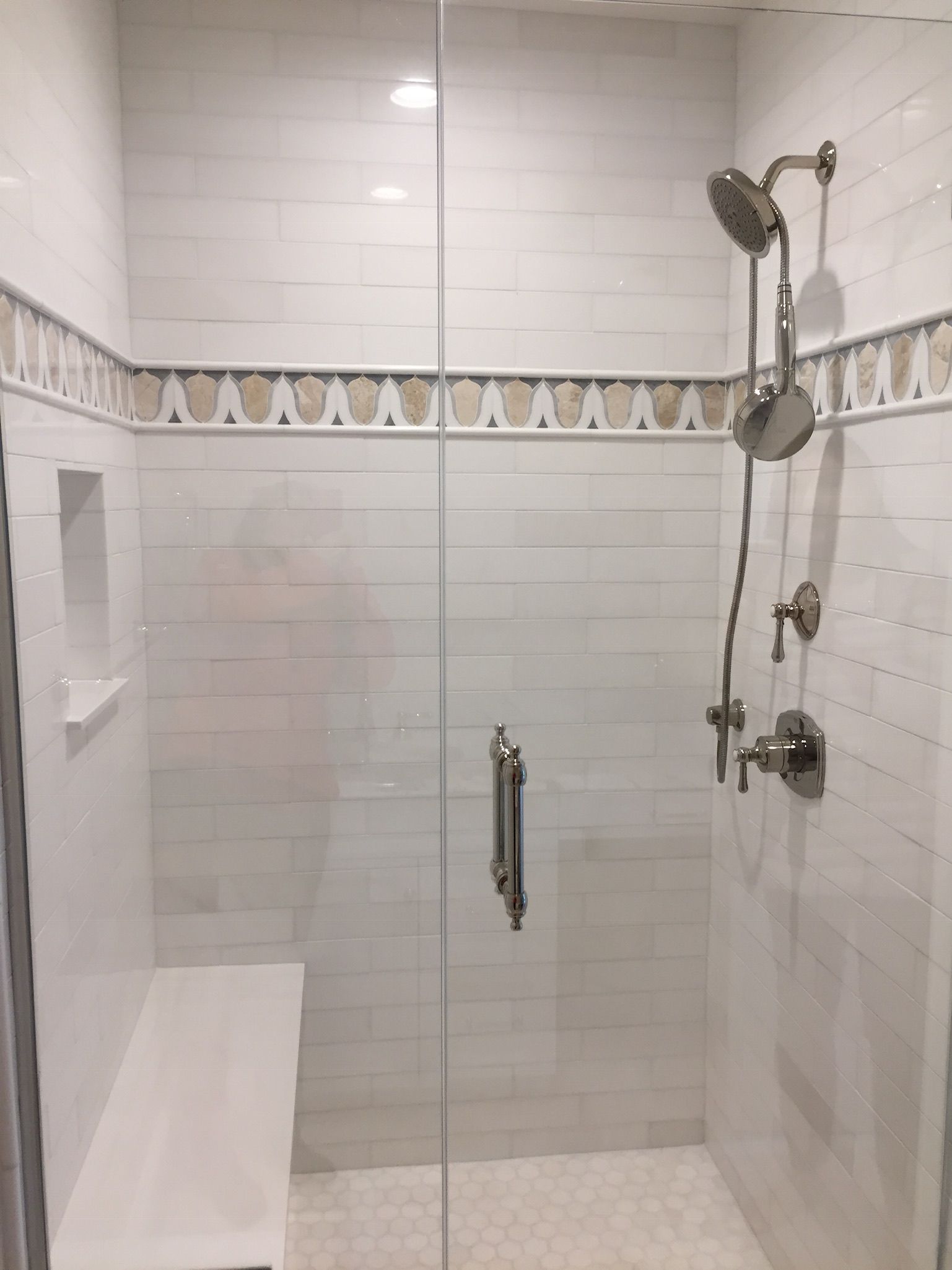 A shower with a bench and a shower head