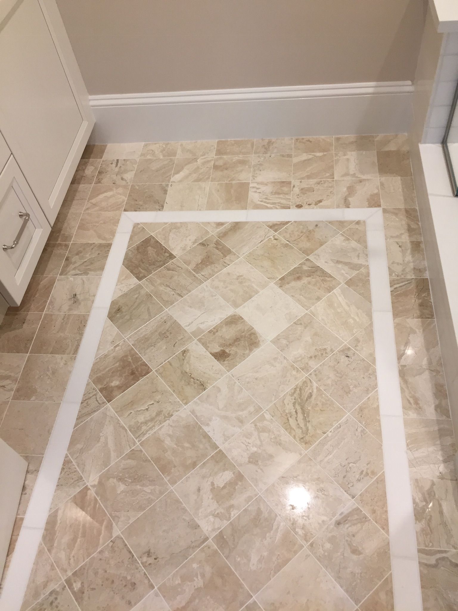 A bathroom floor with a herringbone pattern and a white border.