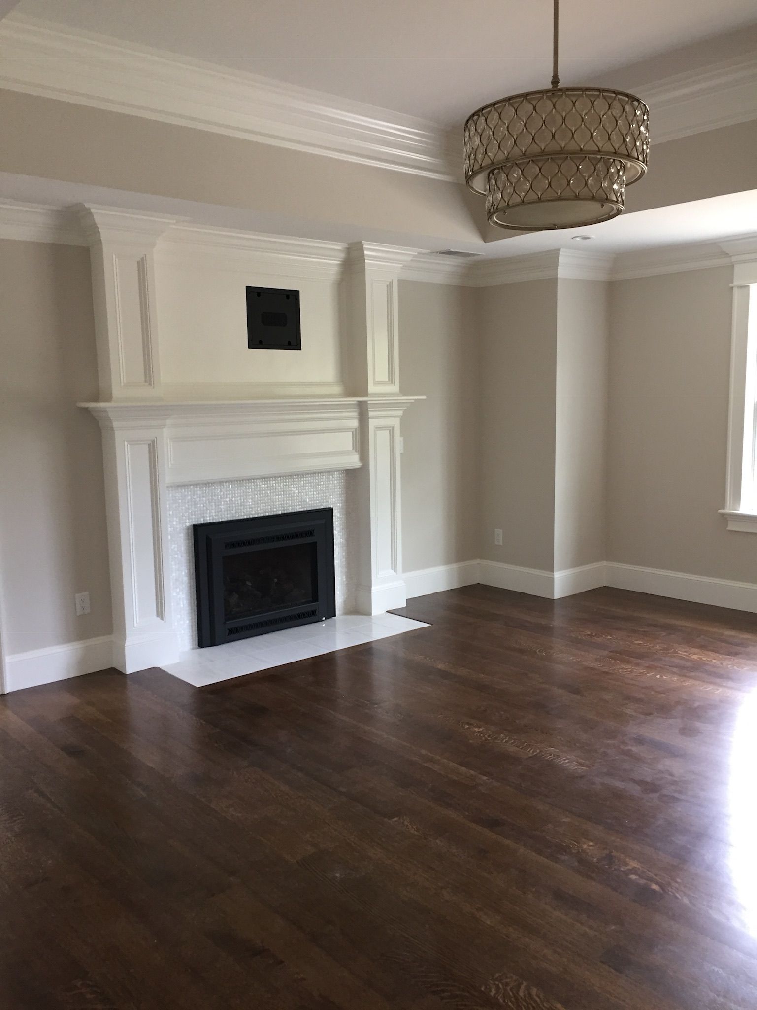 An empty living room with a fireplace and a chandelier.