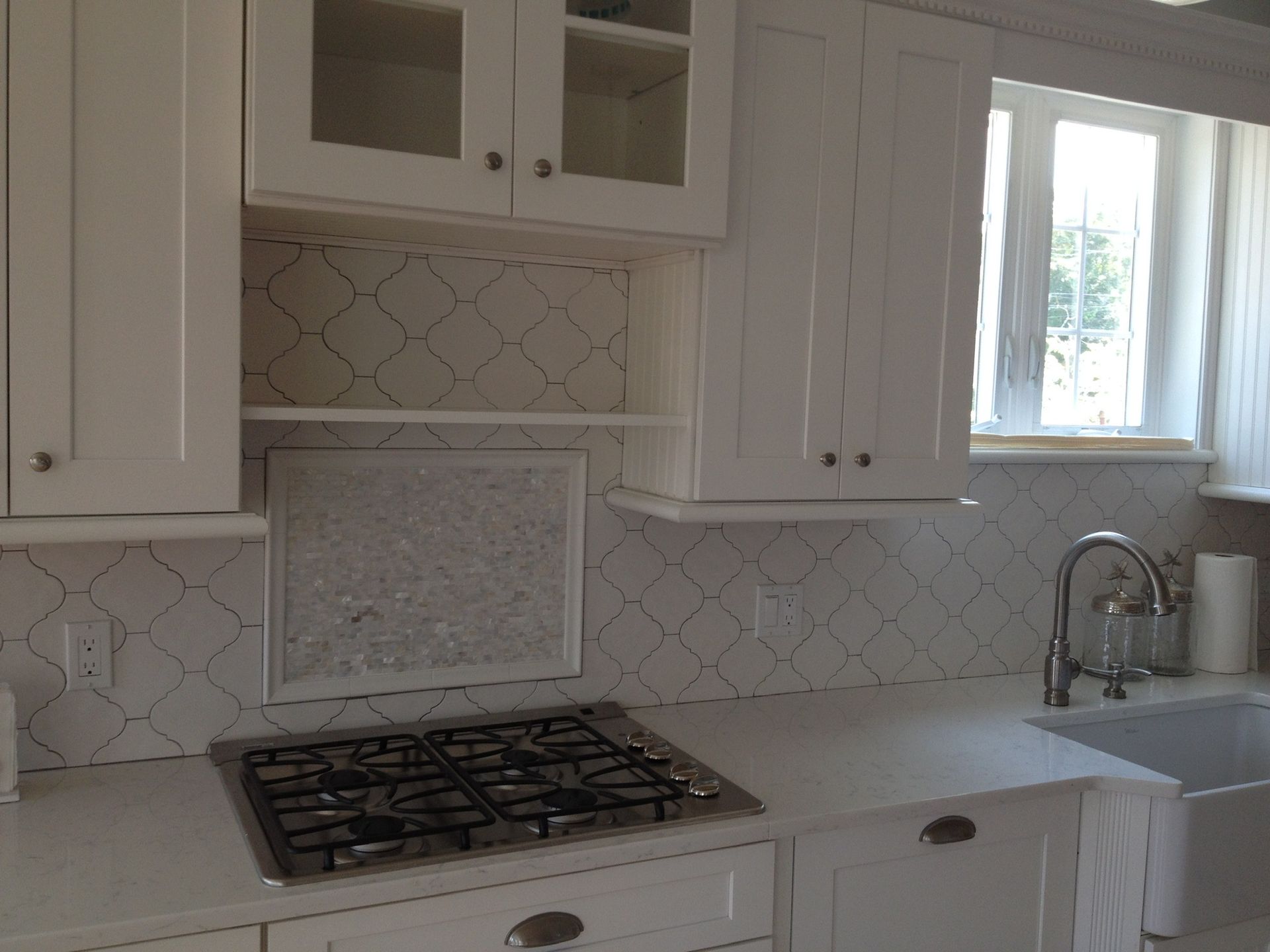 A kitchen with white cabinets and a stove top oven