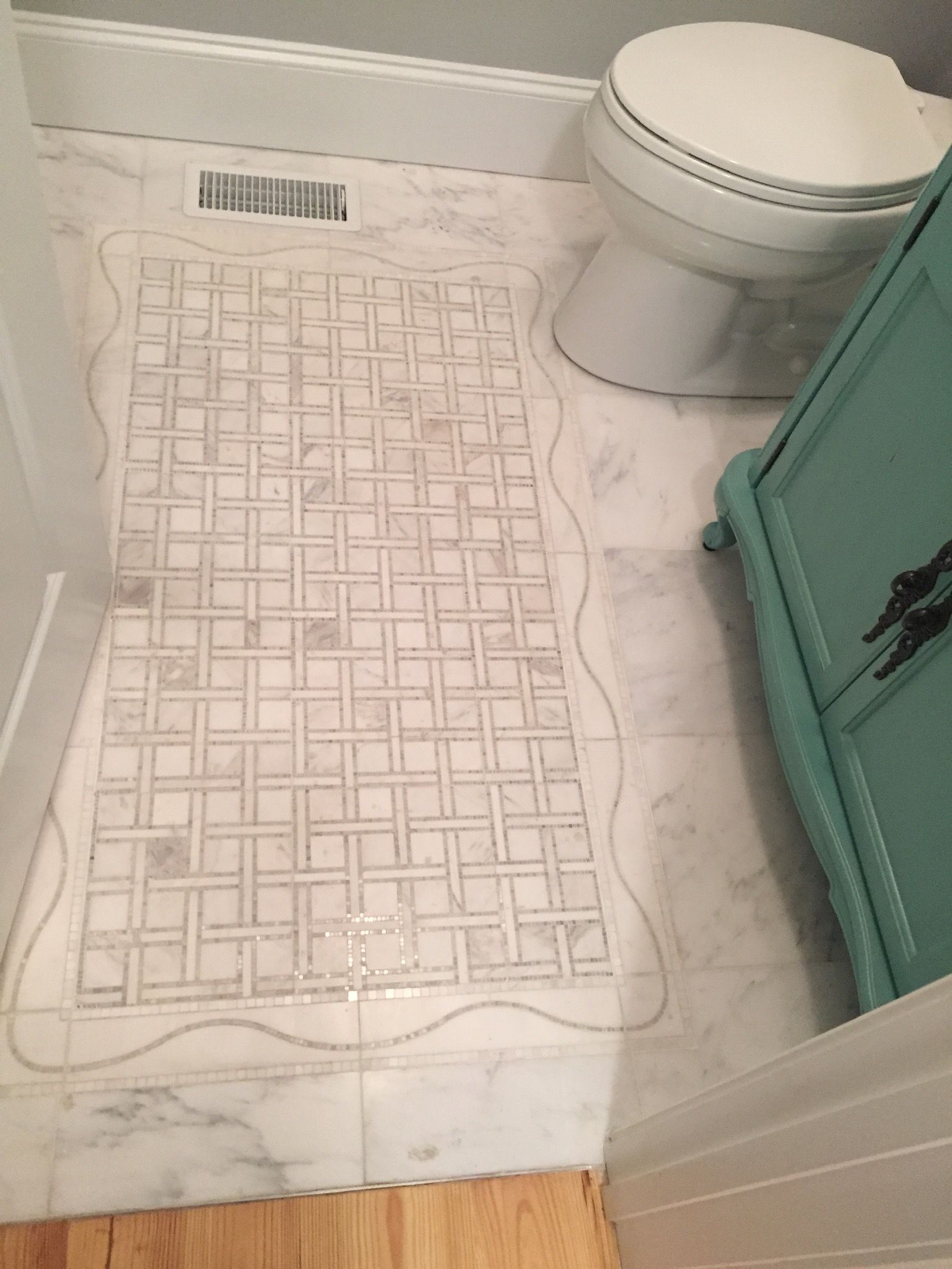 A bathroom with a toilet and a rug on the floor