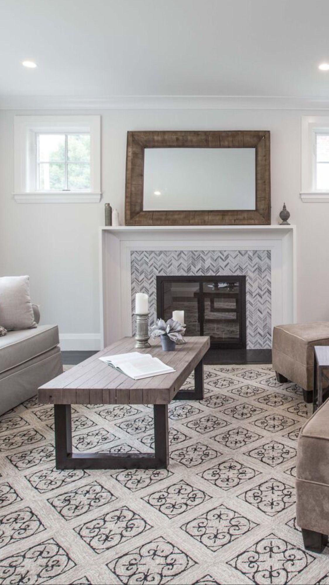 A living room with a fireplace , coffee table , chairs and a mirror.