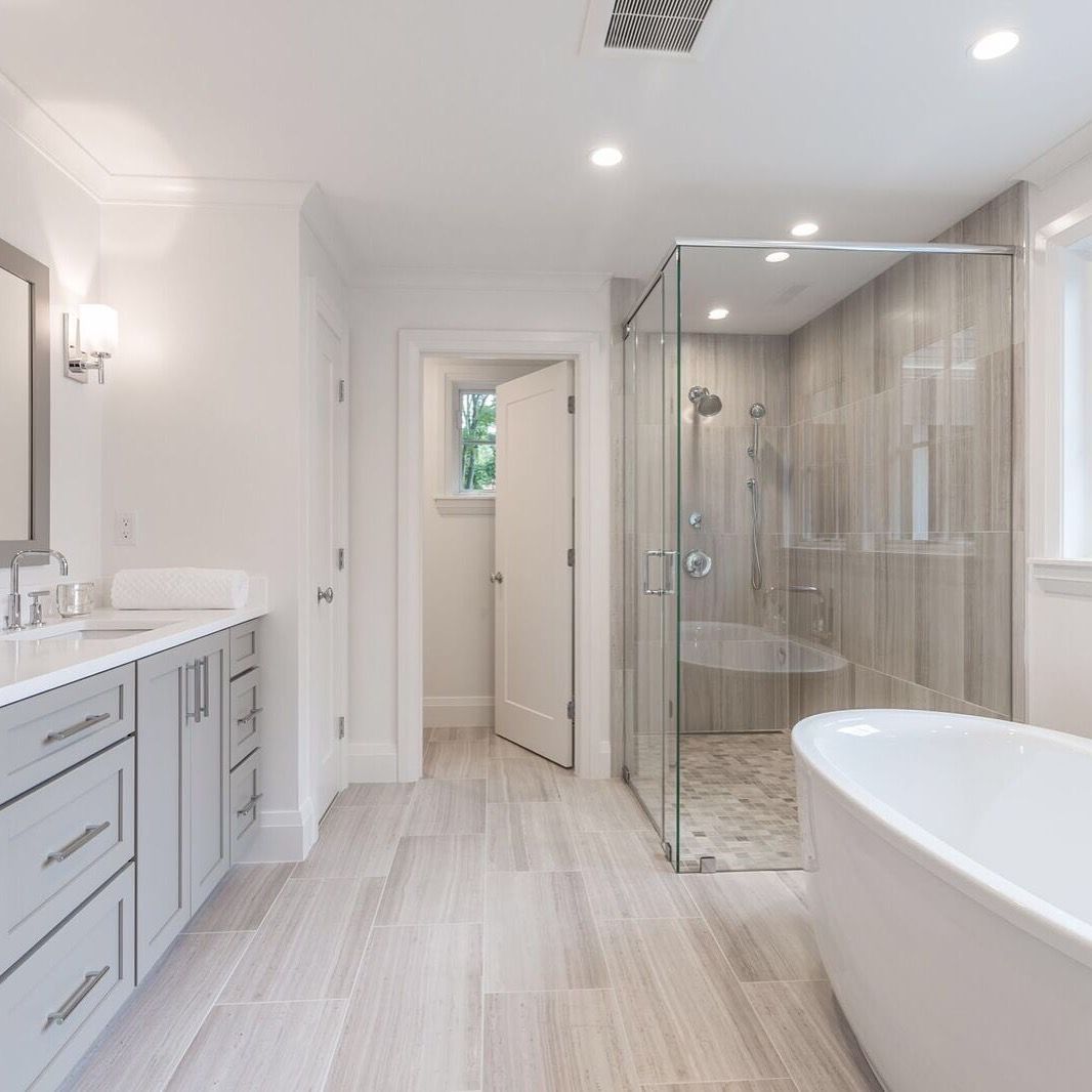 A bathroom with a tub , sink , shower and mirror.